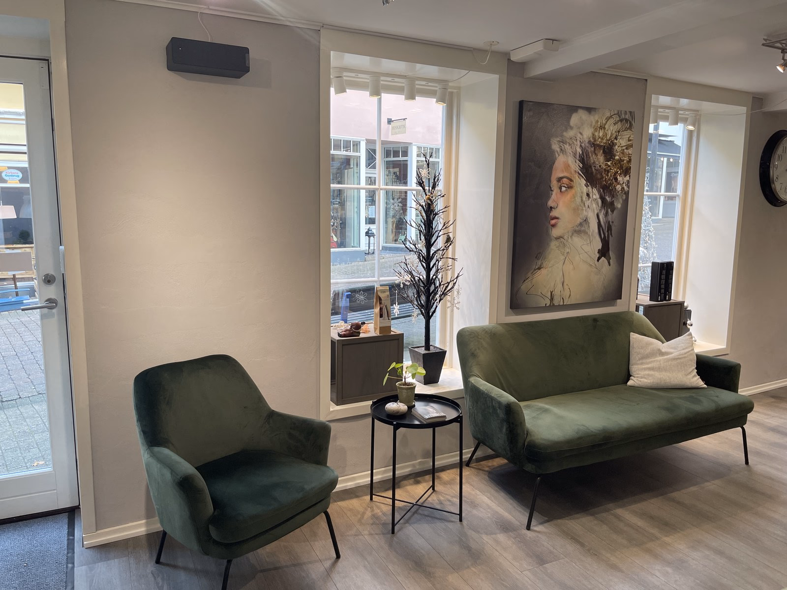 Loungezone hos Frisør Nefertete med grøn velour-sofa og kunstmaleri — rummet hvor Stilletid finder sted