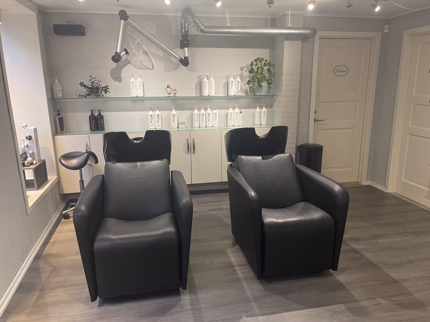 Vaskeområdet hos Frisør Nefertete — to sorte massagestole til afslappende skylning